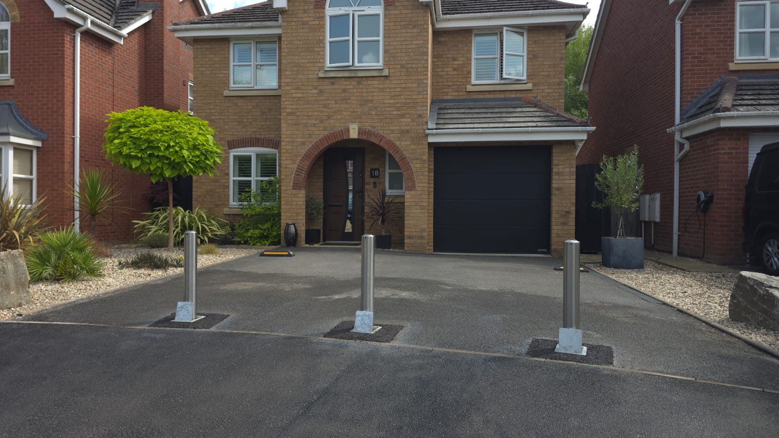 Three stainless steel telescopic security bollards installed across a private driveway